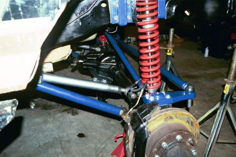1994 Ford Bronco - Close-up of a vehicle's front suspension system, a red coilover shock absorber and blue control arms.