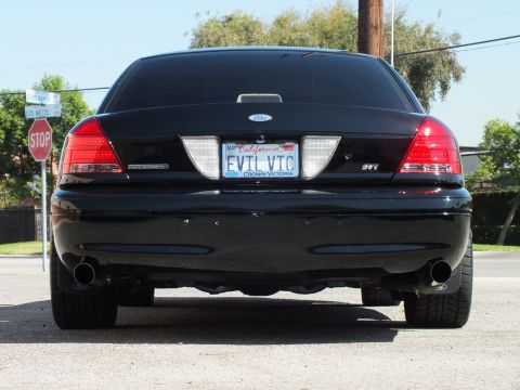 2003 Ford Crown Victoria - Straight rear of a black Crown Victoria with SVT badge and California EVIL VIC plate near a stop sign.