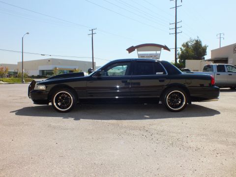 2003 Ford Crown Victoria - Profile of a black sedan fitted with a chrome push bar and black wheels with whitewall tires.
