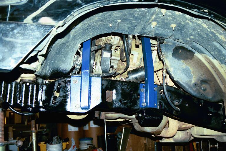 Blue tubular brace legs bolted to a black frame rail with fabricated steel gusset plates