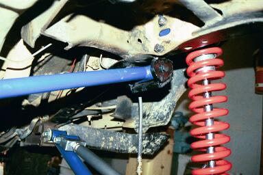 1994 Ford Bronco - Close-up view of vehicle suspension components, including a red coil spring and blue control arm.