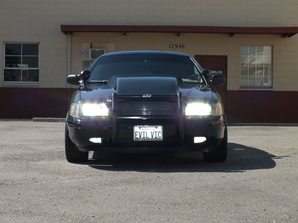 Black Crown Victoria head-on with headlights on, billet grille and EVIL VIC plate
