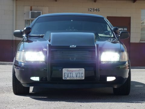 2003 Ford Crown Victoria - Close front view of a black sedan; plate frame reads Ford Crown Victoria, plate EVIL VIC.