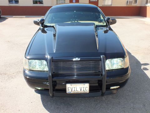 2003 Ford Crown Victoria - Front quarter of a black sedan; plate frame reads Crown Victoria, vanity plate EVIL VIC.