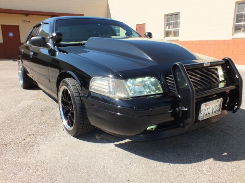 2003 Ford Crown Victoria - Low front-quarter view of the black sedan; chrome push bar and a front plate marked EVIL VIC.