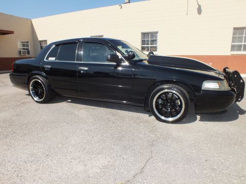 2003 Ford Crown Victoria - Side-front angle of the black sedan, push bar mounted up front and a lowered, blacked-out stance.