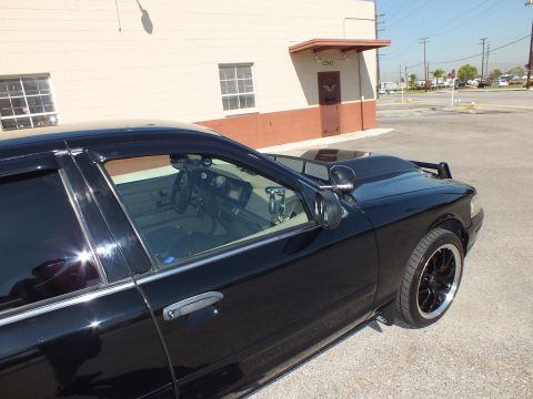 2003 Ford Crown Victoria - Tight rear-quarter view of the black sedan, side mirror and tinted windows with a decklid lip.