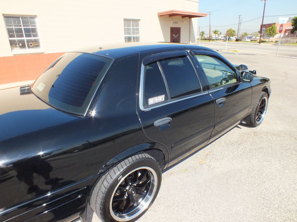 Black sedan rear three-quarter with tinted windows and black wheels in parking lot