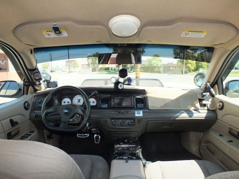 2003 Ford Crown Victoria - Tan dash and Ford steering wheel of the Crown Victoria viewed from the back seat.
