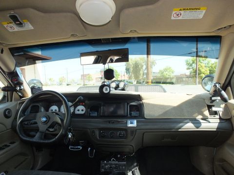 2003 Ford Crown Victoria - Passenger-side dash view of the tan interior with steering wheel and aftermarket gauge pods.