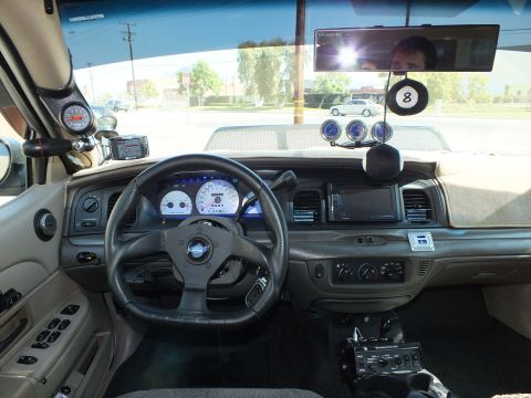 2003 Ford Crown Victoria - Driver cockpit showing a leather-wrapped wheel, pillar gauge and an 8-ball hanging accessory.