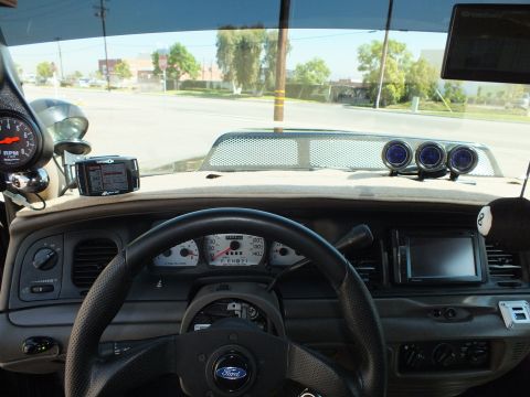 2003 Ford Crown Victoria - View over the Ford-emblem steering wheel to the gauge cluster and a triple-gauge pod on the dash.