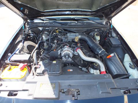 2003 Ford Crown Victoria - Engine bay of the Ford V8 showing a polished intake tube, yellow battery and serpentine pulley.