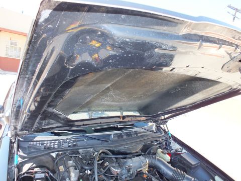 2003 Ford Crown Victoria - View under a raised black hood showing degraded sound-deadening insulation above the engine bay.