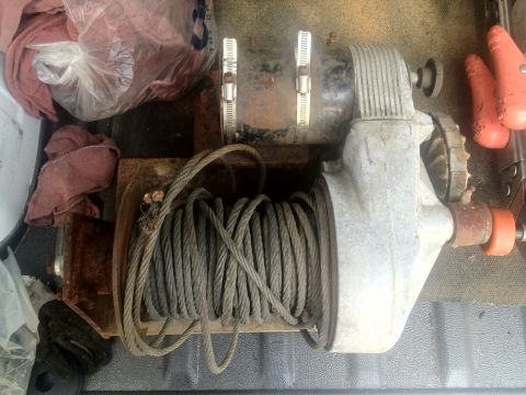 2000 Jeep Wrangler - A winch with a steel cable is visible, along with some rags and a plastic bag, in what appears to be the bed of a truck.