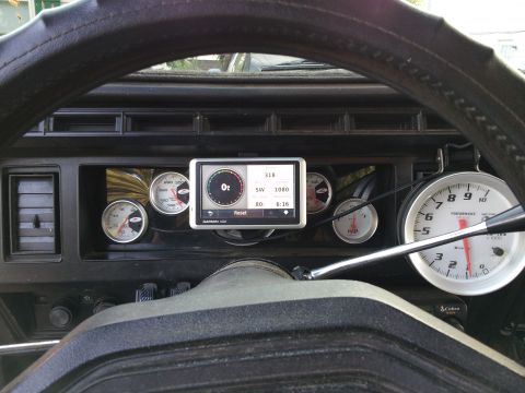 1986 Ford Bronco - The interior of a vehicle shows a dashboard filled with various gauges and a Garmin GPS unit.