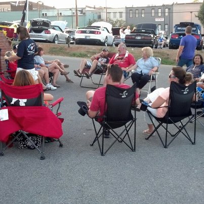 2007 Ford Mustang - Attendees relax at an outdoor car show, with multiple Ford Mustangs parked in the background.