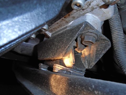 1990 Ford Bronco - Close-up view of a worn engine mount, showing damage to the rubber and metal components.