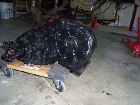1968 Ford Bronco - Transfer case on a dolly in a garage setting. Rear axle assembly is also visible.