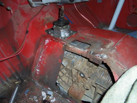 1968 Ford Bronco - The interior of a vehicle displays a manual transmission shifter and modified floor panels, with visible rust and wiring.
