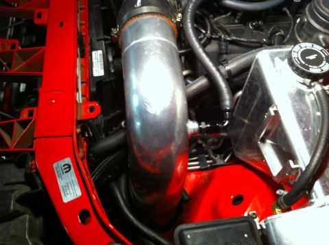 2010 Dodge Challenger - Close-up of a Dodge Challenger engine bay showing intake piping and coolant reservoir.