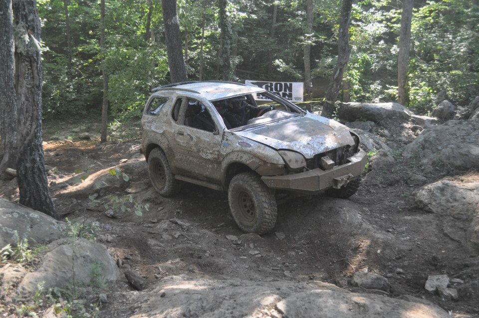 Mud-covered 1999 Isuzu Vehicross on rocky terrain, front bumper modified, windshield cracked