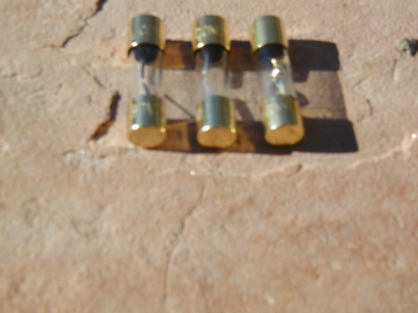 Three glass fuses with brass caps on a textured surface