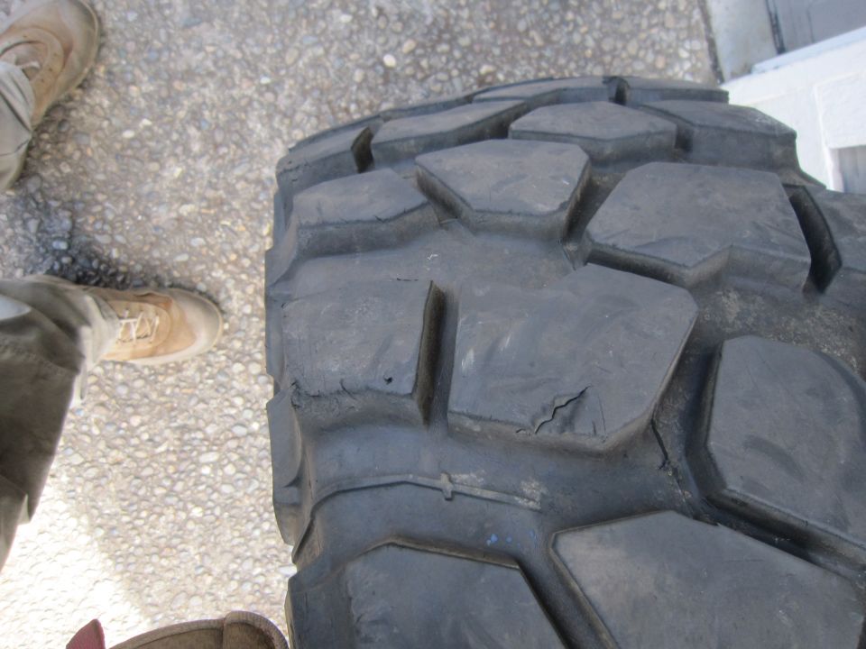 worn off-road tire with large, blocky tread and visible cracking on sidewall