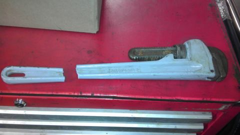 1989 Ford Bronco - A broken pipe wrench lies on a red surface, with the handle snapped into two pieces.