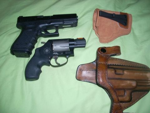 1987 Ford F-250 - A collection of firearms and their carrying holsters are laid out on a textured green background.