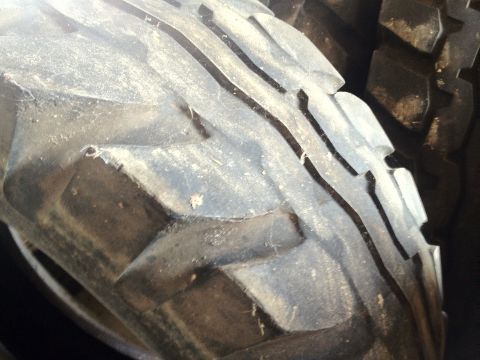 2000 Jeep Wrangler - A close-up view of a tire's tread pattern, partially obscured by dust and dirt, with a website watermark visible.