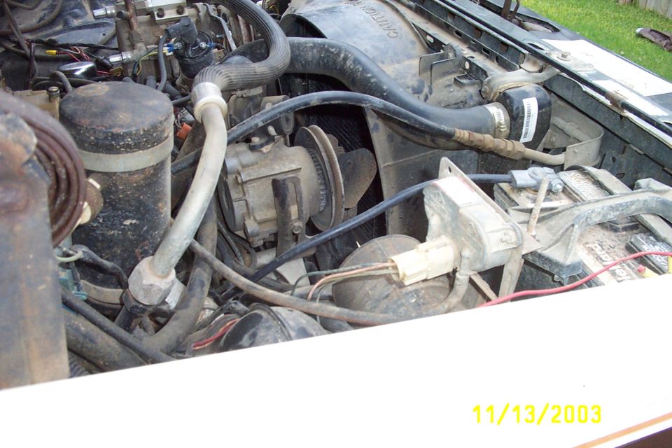 1982 Ford Bronco engine bay with visible battery, fan, and hoses