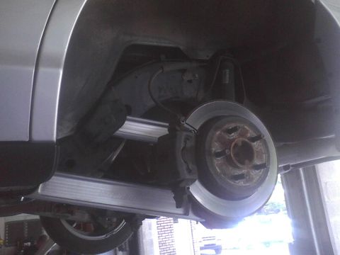 2003 Ford Crown Victoria - Underside view of a vehicle's rear brake assembly, showing the rotor and caliper.