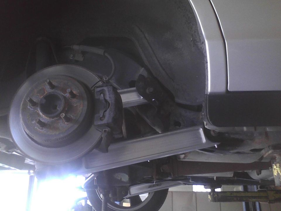 Underside view of a vehicle's rear brake rotor and caliper assembly