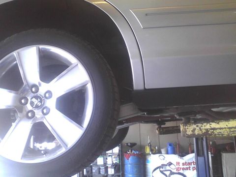 2003 Ford Crown Victoria - A silver sedan is raised on a mechanic's lift, showing its wheel and undercarriage.