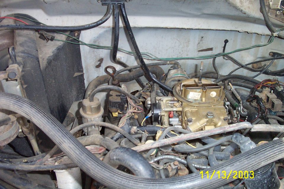 Engine bay with carburetor and hoses