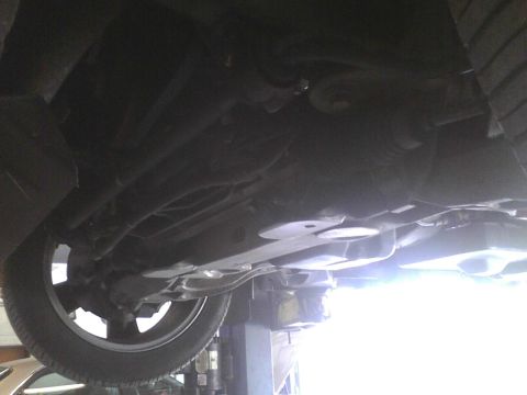 2003 Ford Crown Victoria - The underside of a vehicle is viewed from below while it is elevated on a lift.