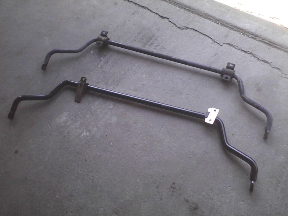 Two black sway bars on a concrete surface. One is above the other