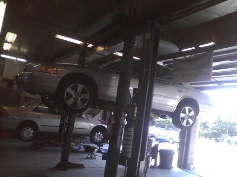 2003 Ford Crown Victoria - A silver 2003 Ford Crown Victoria is raised on a car lift in a service bay.