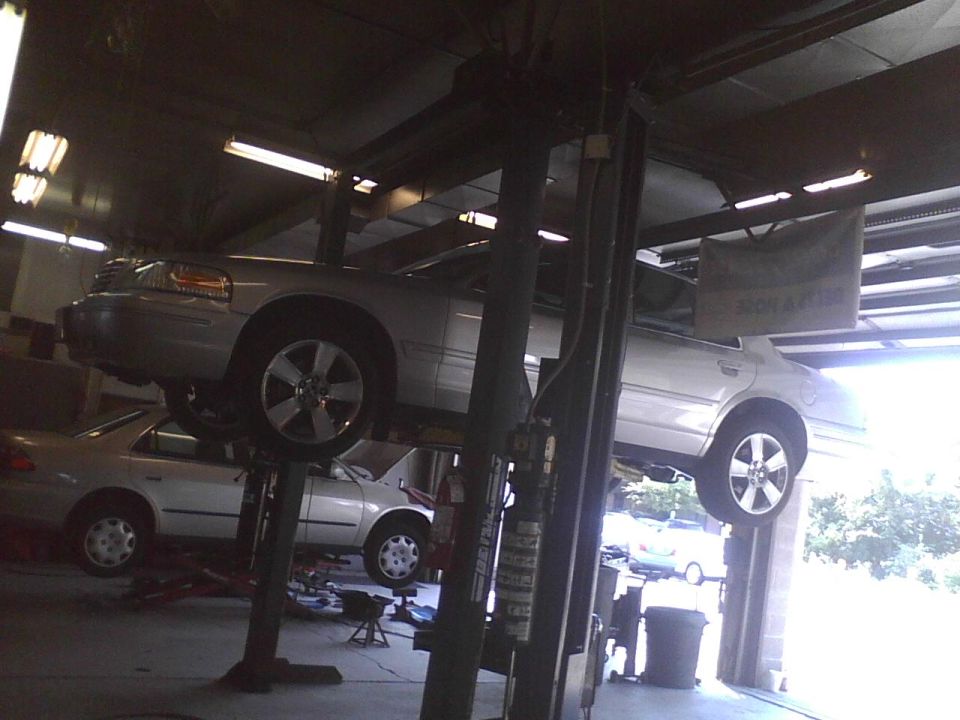 2003 Ford Crown Victoria on a car lift in a garage, another car is visible below
