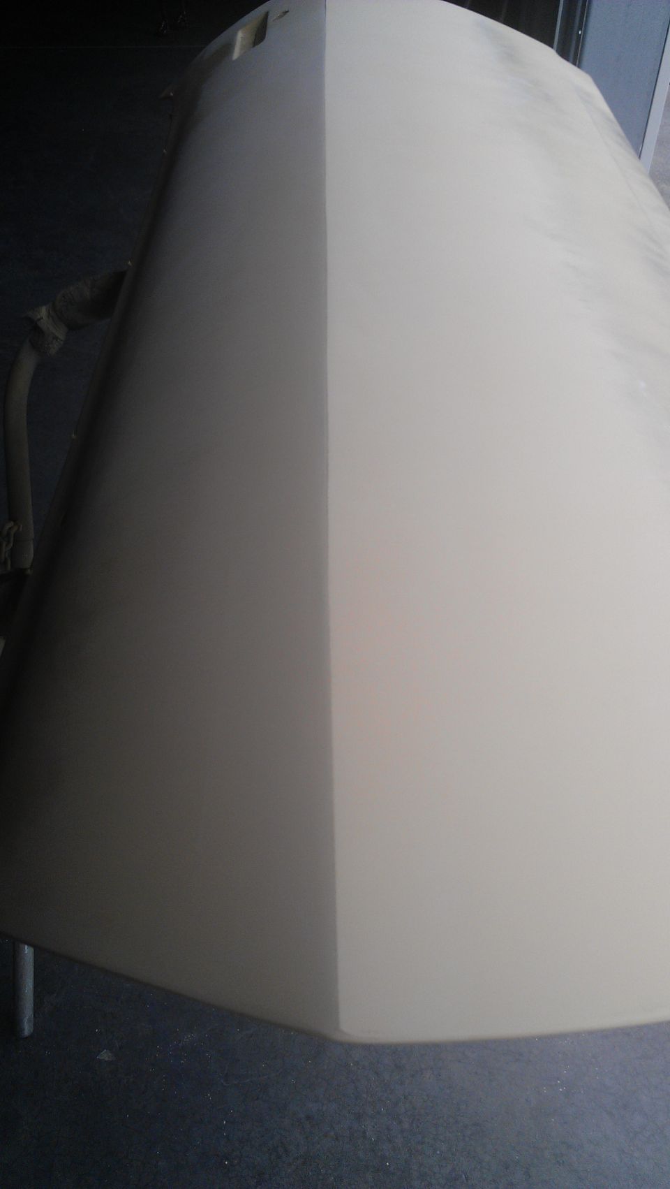 Car hood, half primer, half painted, on sawhorses