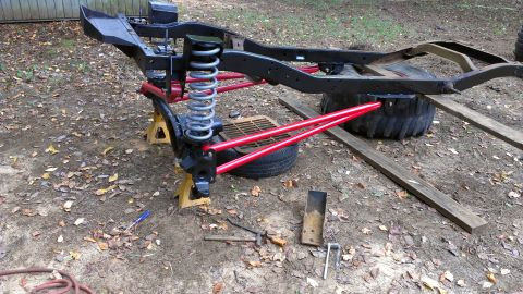 1978 Ford Bronco - The chassis of a vehicle is shown on jack stands, with red suspension components visible.