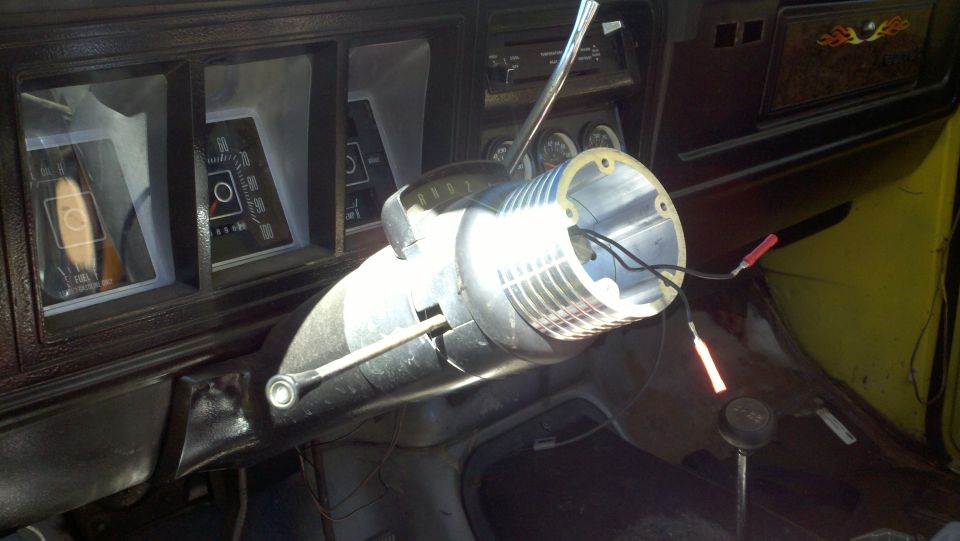 Interior shot of a vehicle with the steering column removed, showing exposed wires and the dashboard gauges