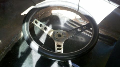 1978 Ford Bronco - A black steering wheel with a three-spoke design is shown, with visible cutouts on the spokes.