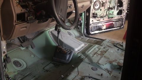 1995 Ford Bronco - The interior of a 1995 Ford Bronco is visible, with the door panel removed and the floor stripped bare.