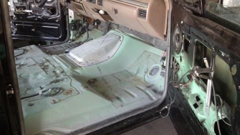1995 Ford Bronco - Interior of a vehicle undergoing restoration, with the floor stripped and door panel removed.