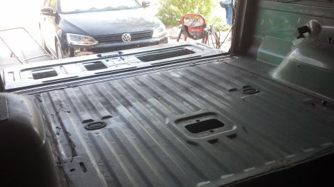 1995 Ford Bronco - The interior of a truck bed is shown, with a Volkswagen Jetta visible in the background.