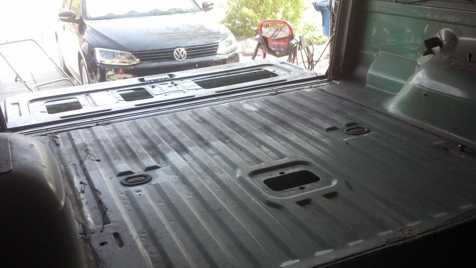 Empty truck bed with ribbed floor, a black Volkswagen Jetta parked behind it