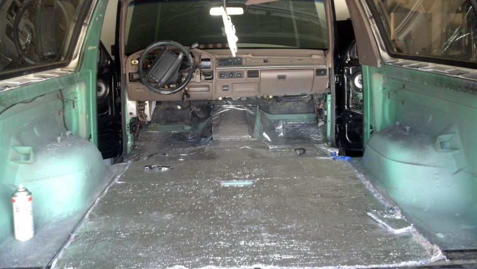 Interior of a green SUV with seats removed and sound deadening material on the floor