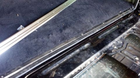 1995 Ford Bronco - The interior cargo area of a 1995 Ford Bronco shows black carpeting and polished metal trim along the edge.